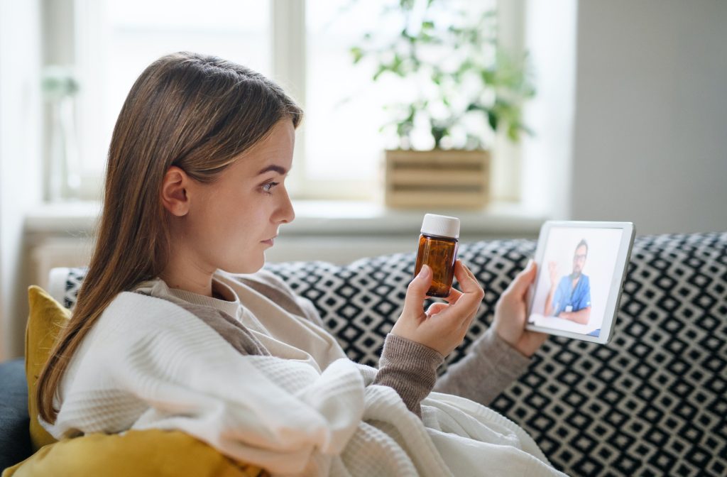 young woman having video call with doctor on tablet at home online consultation concept